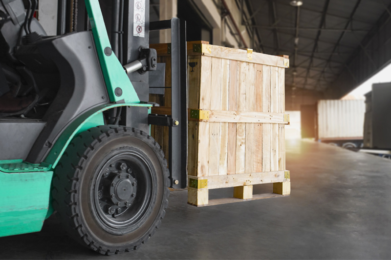 Carretilla elevadora verde con caja cargada.