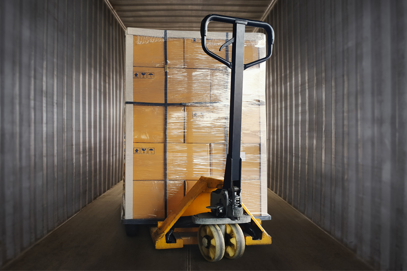 Transpaleta manual cargando cajas de camión.