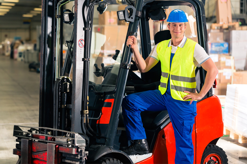 Operario posando sonriente en carretilla elevadora.